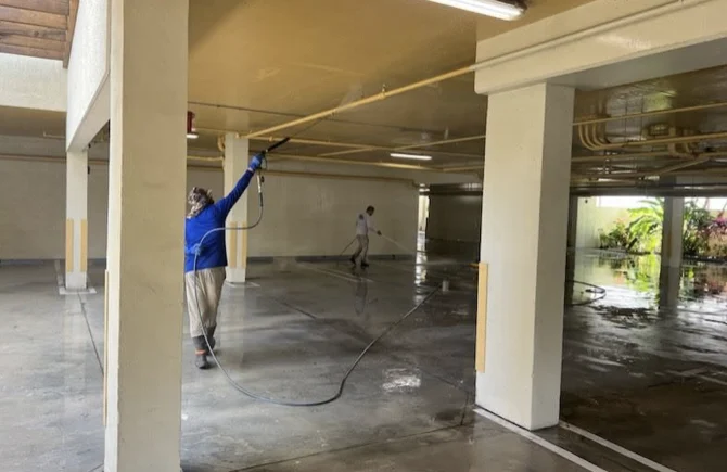 Technician cleaning overhead pipes in the Coral Gables parking garage
