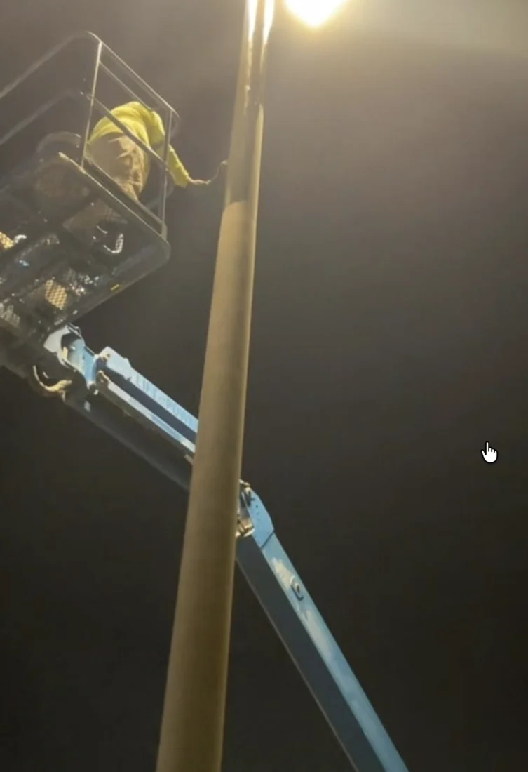 Boom-lift work beside a Costco light pole during overnight restoration
