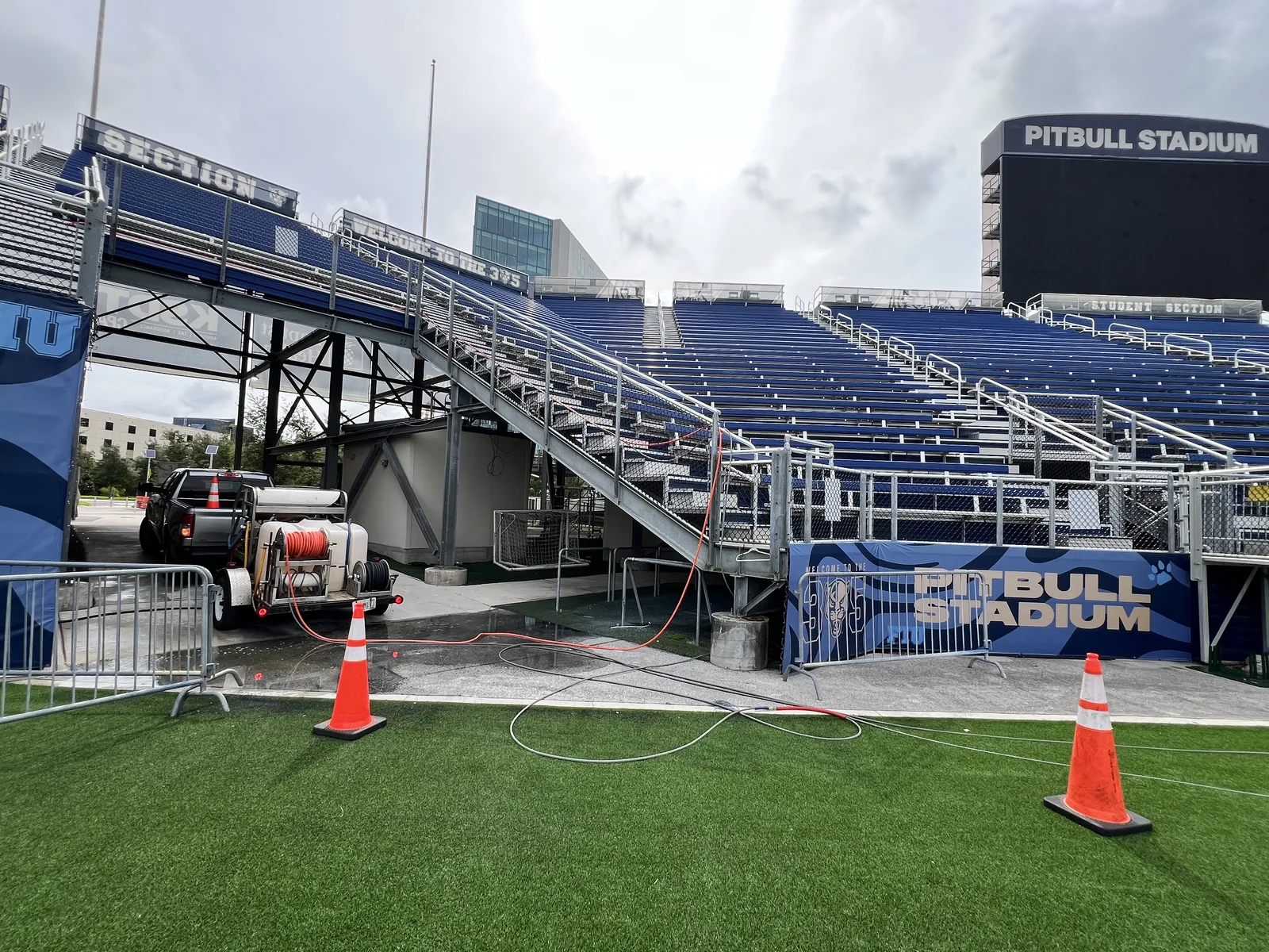 Pressure washing trailer, hoses and work-area cones beside the Pitbull Stadium seating