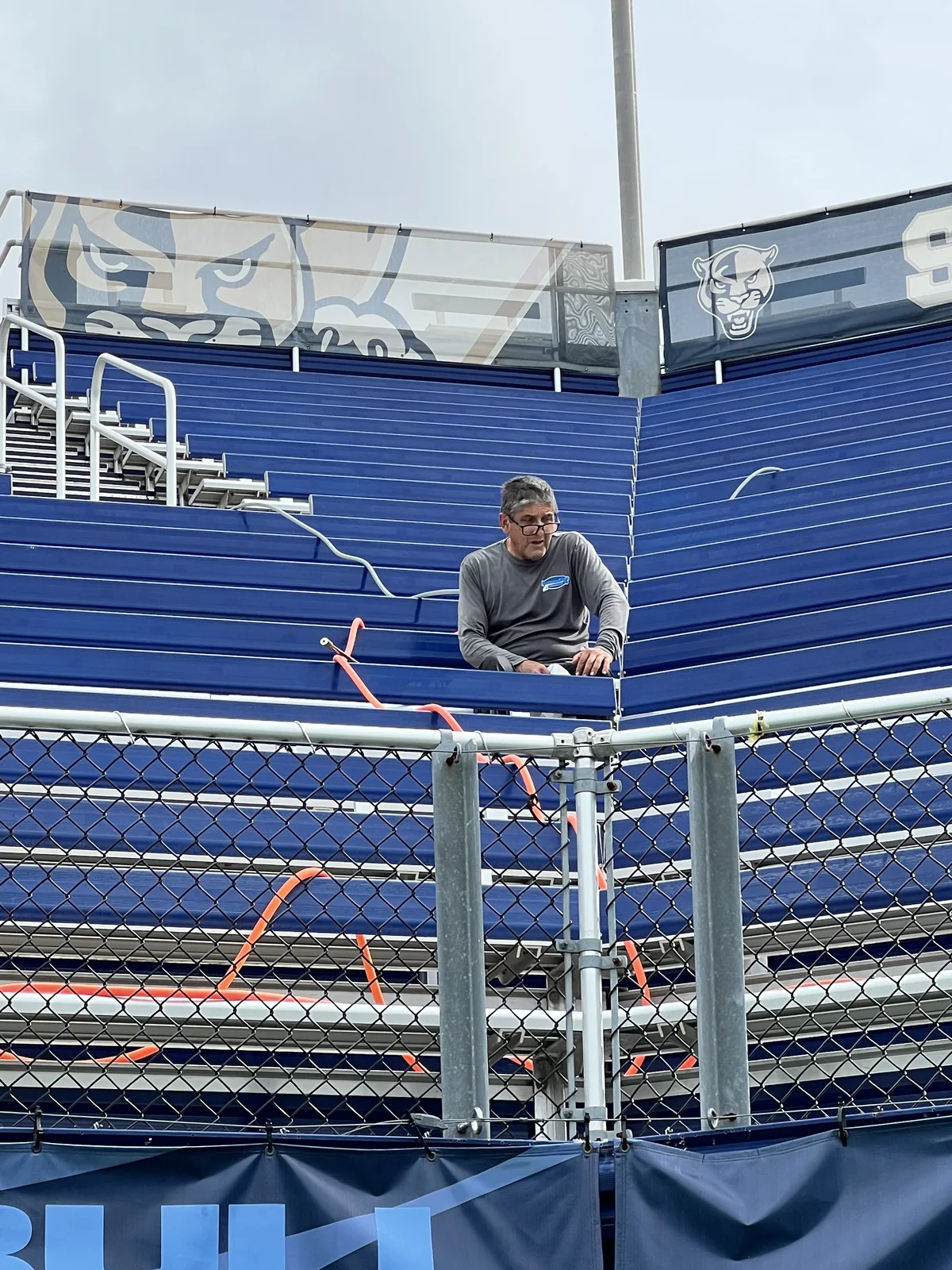 Pressure Kleen crew member with a cleaning hose among FIU stadium seating
